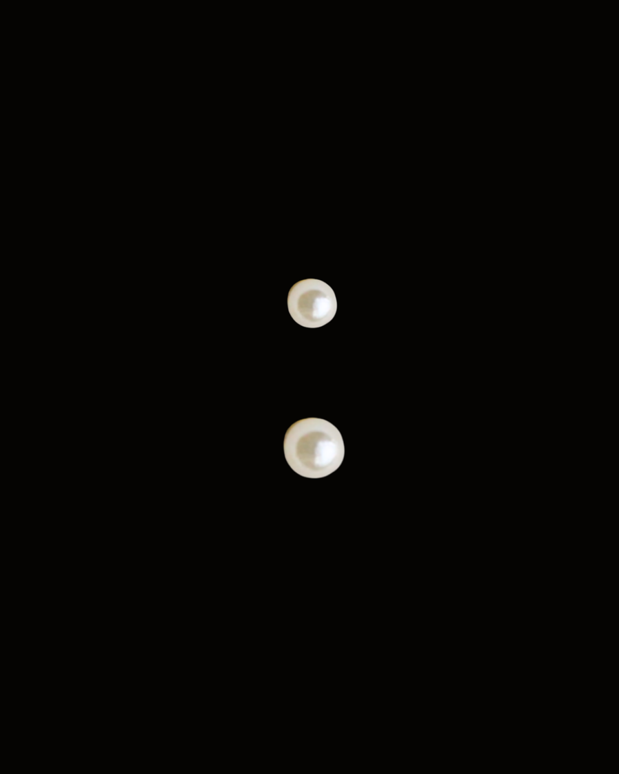 Two pearl earrings on a black background
