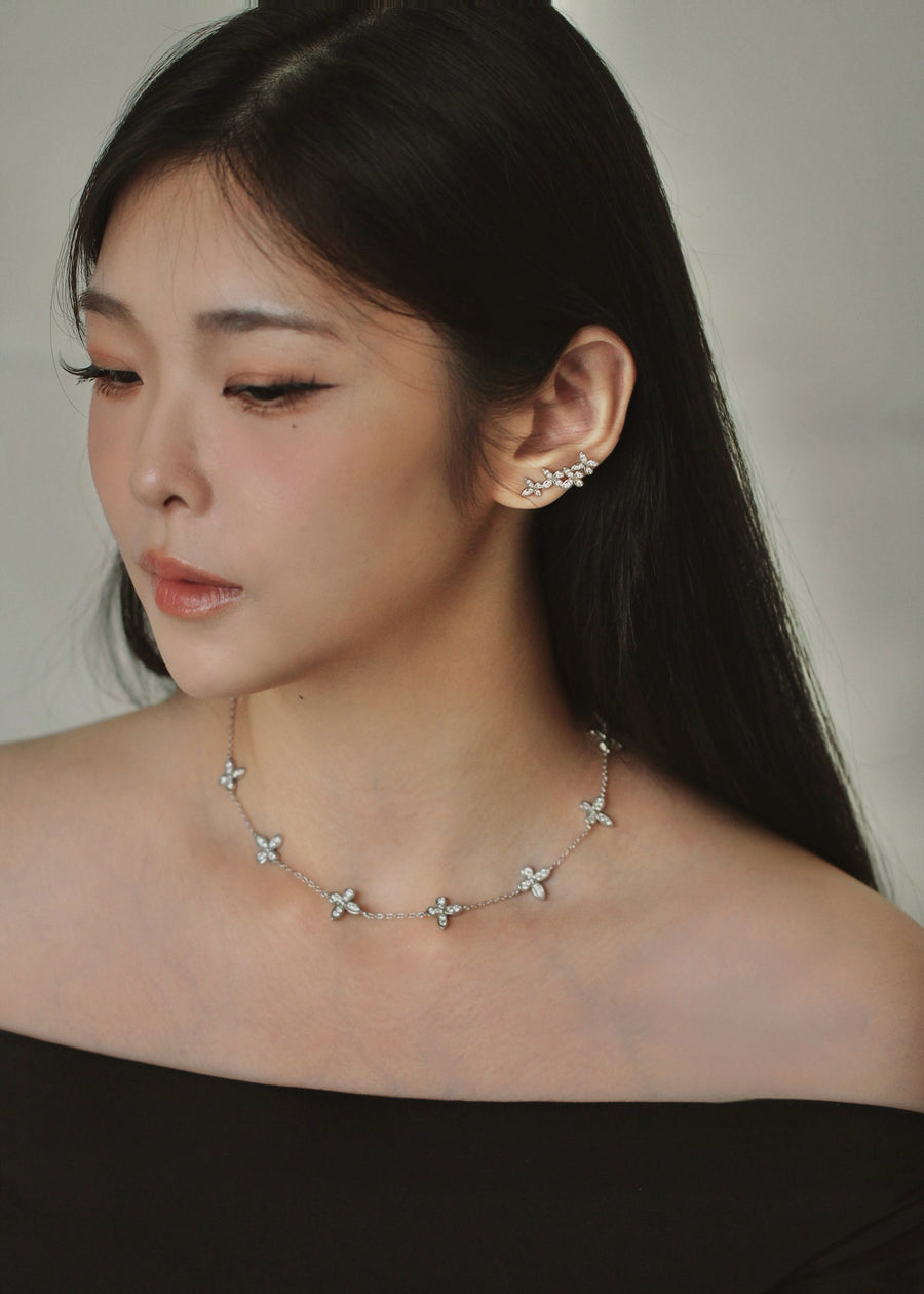Woman wearing a butterfly motif necklace and earrings with a neutral background
