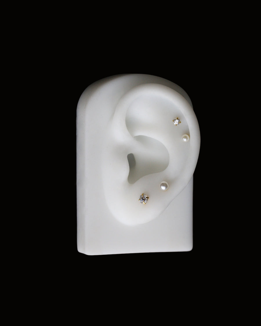 Model of an ear with embedded earrings on a black background