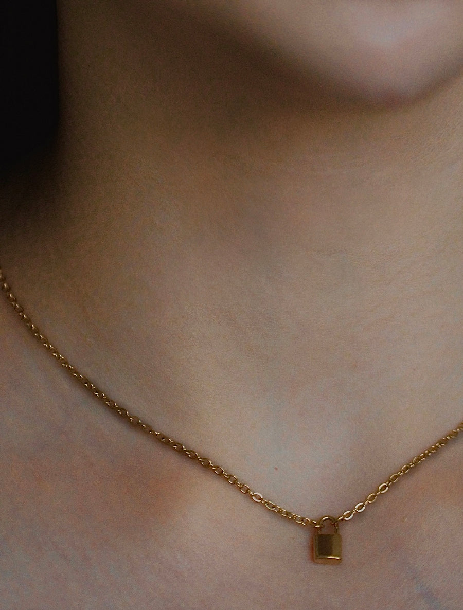 Gold necklace with a small pendant on a person's neck