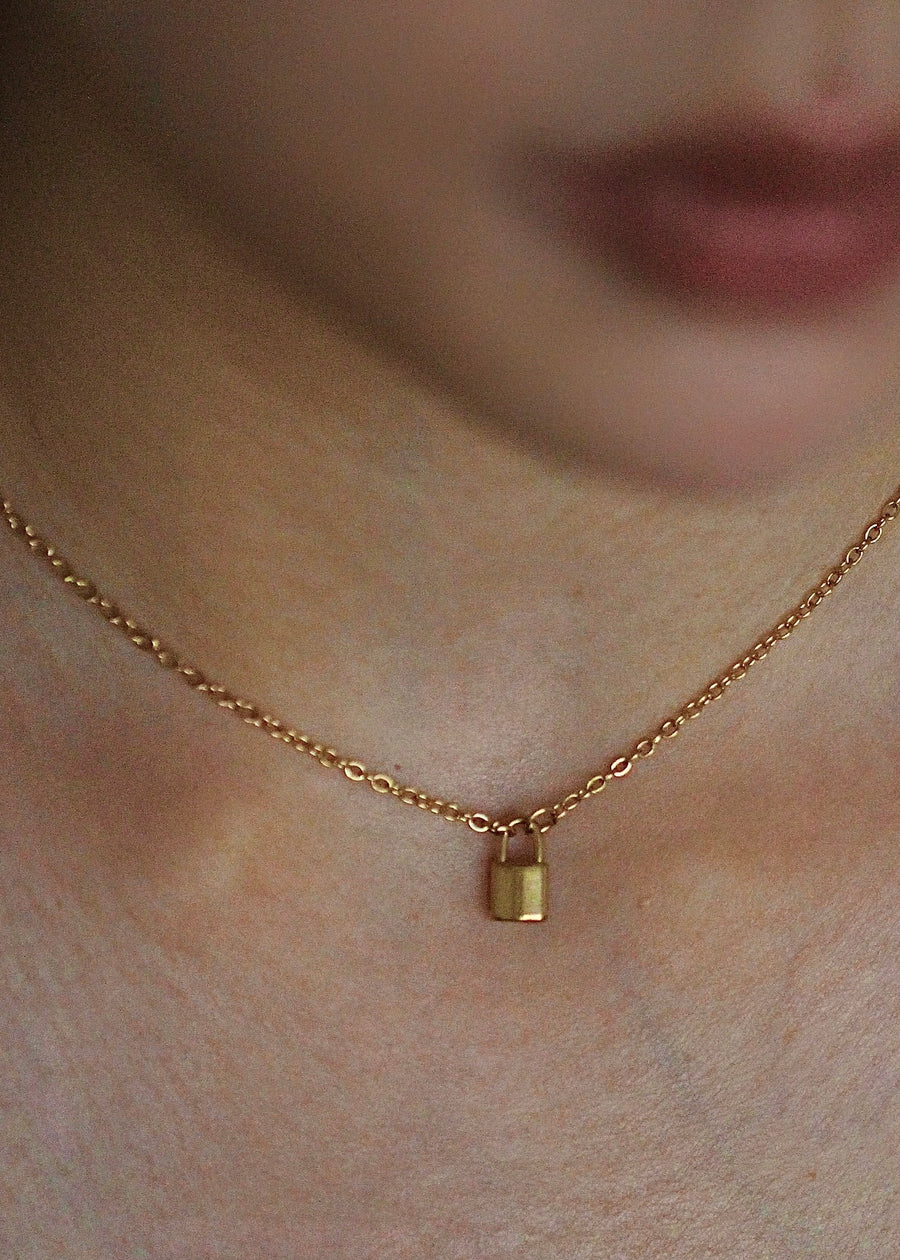 Gold necklace with a small pendant on a person's neck